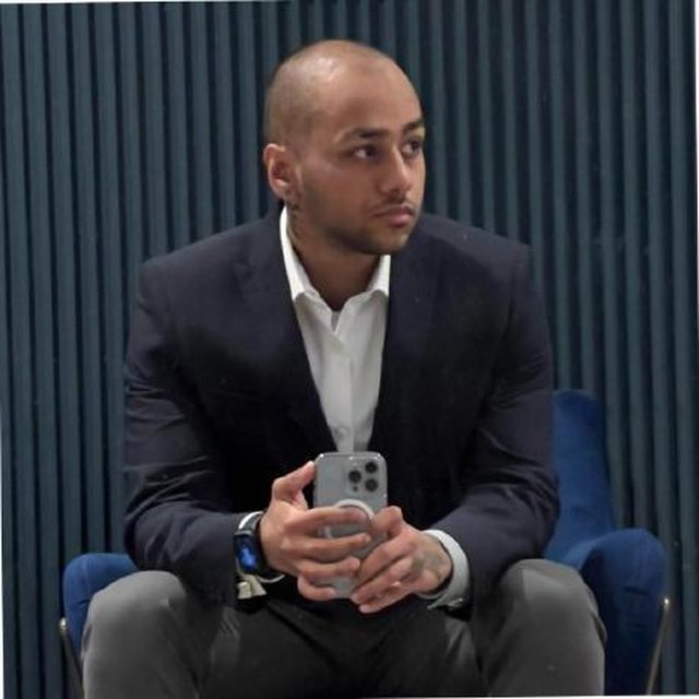 Renato Gusani, seated, in a navy suit jacket over a white shirt.